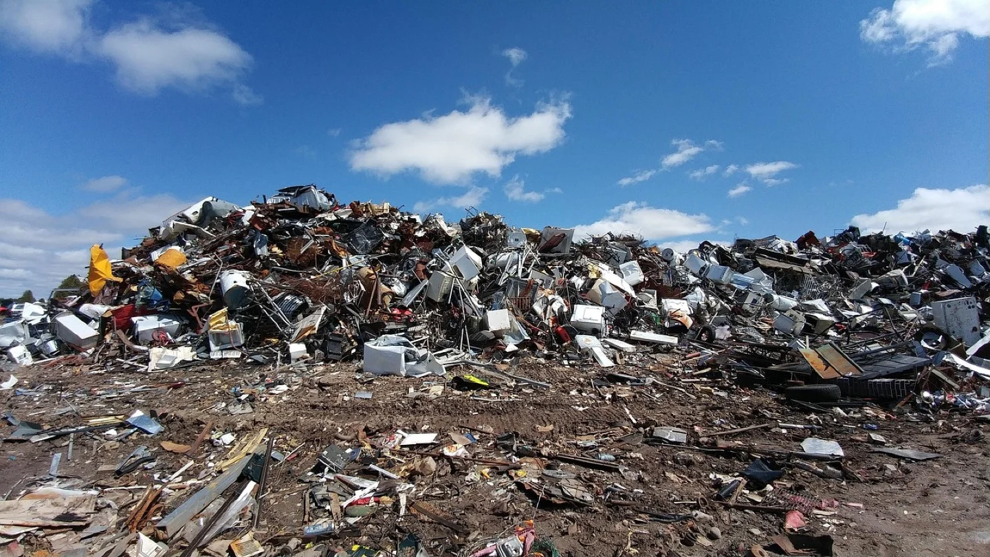 Large mixed-material recovery and recycling site under a blue sky.