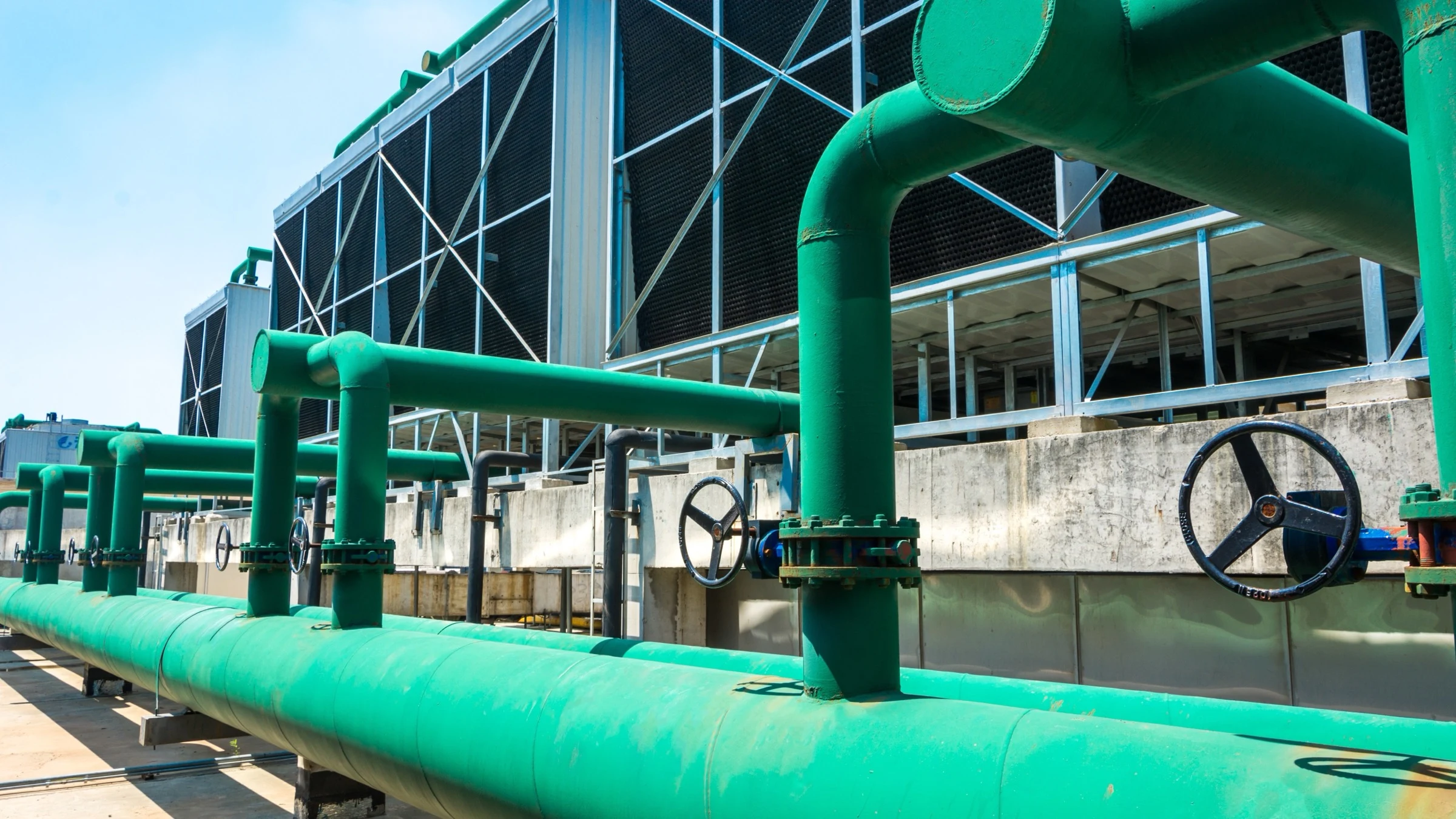 Large green cooling pipes and cooling towers beside a data-center building