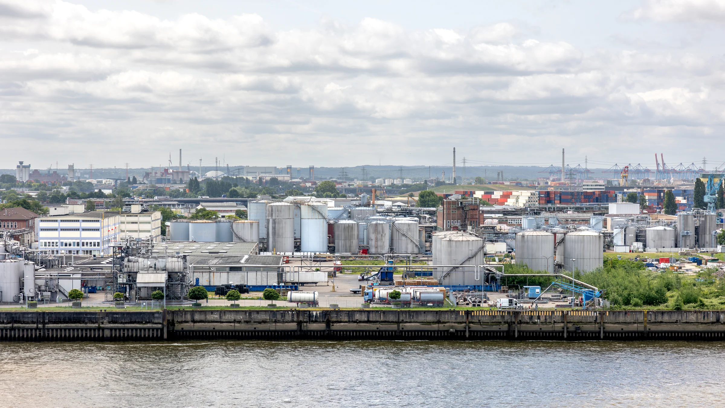 Industrial facility beside water, storage tanks and large pipework in Hamburg, Germany.