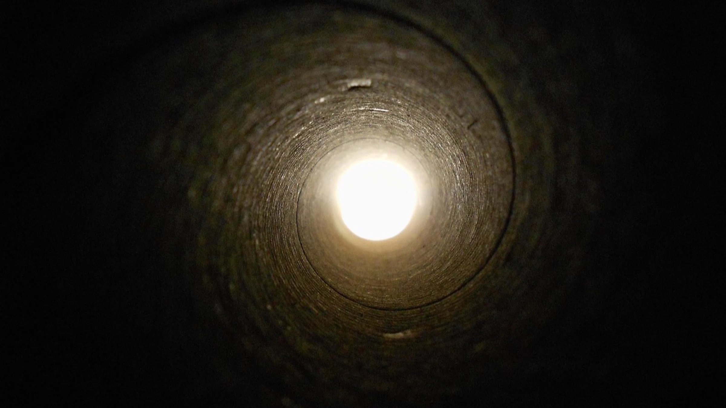 View through a large underground pipe or service tunnel.