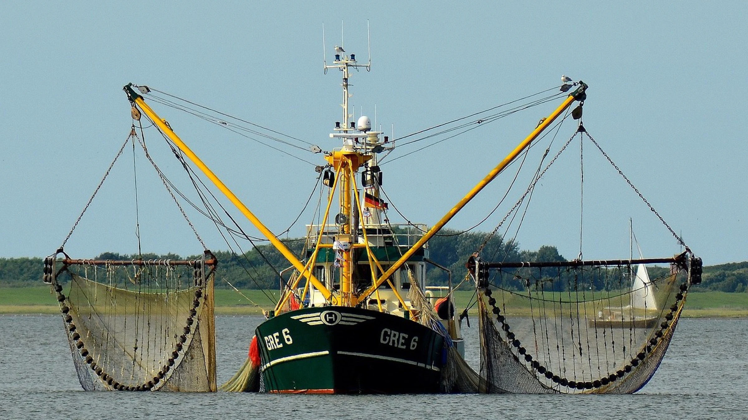 Commercial fishing vessel with nets extended on both sides.