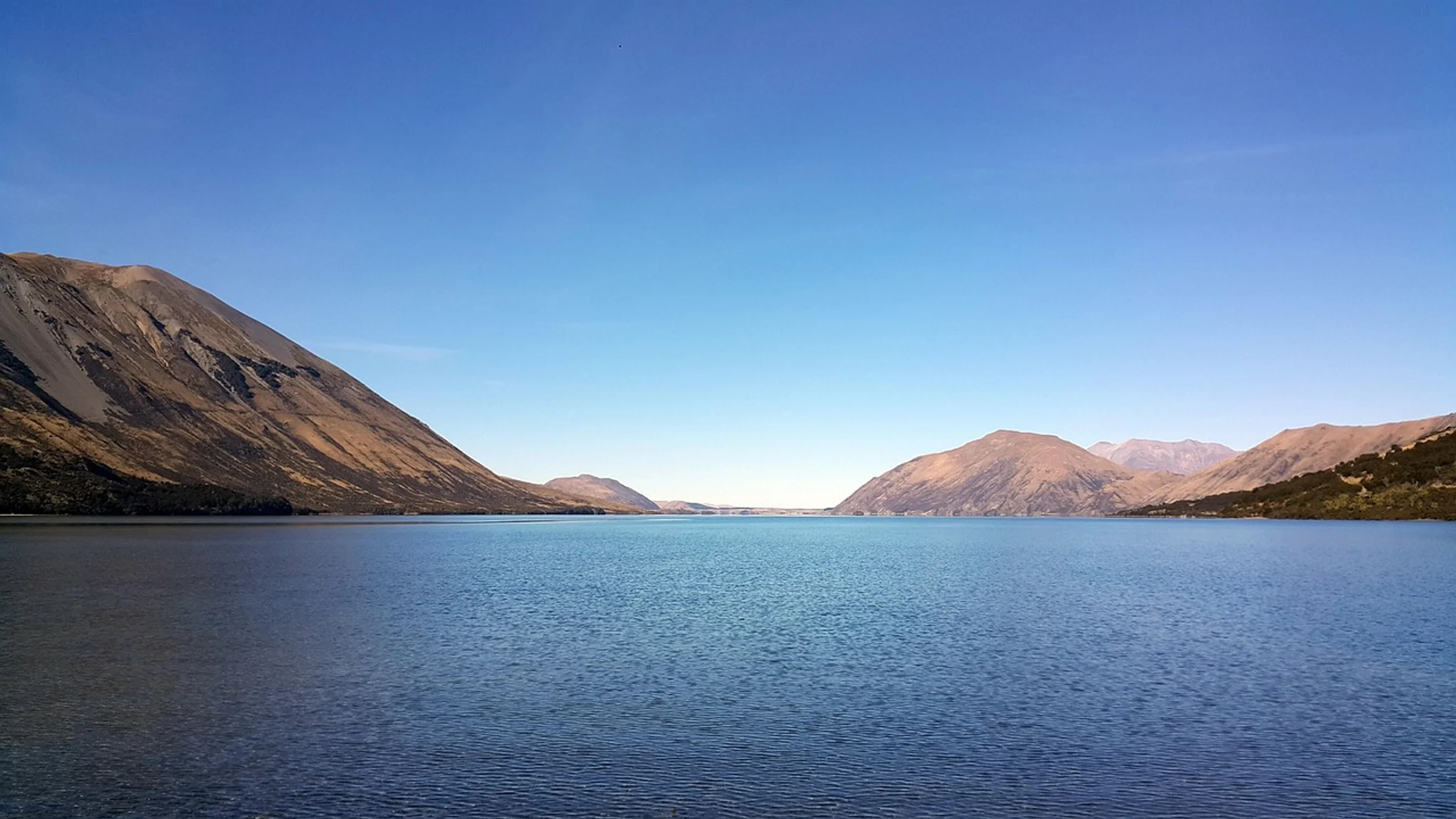 Lake Coleridge in Canterbury, New Zealand, between dry mountain slopes.