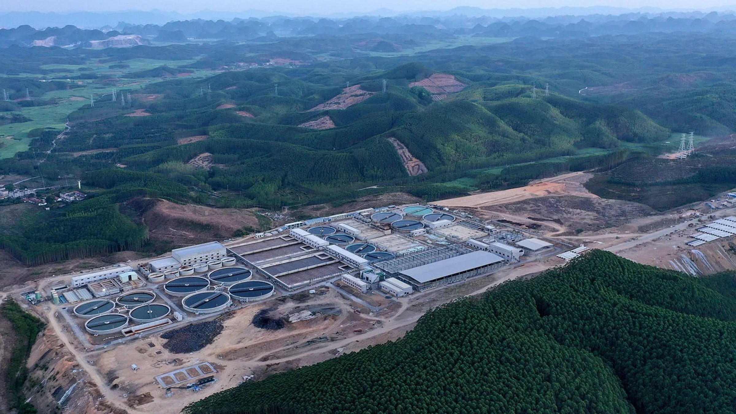 Aerial view of a wastewater treatment plant with circular settling tanks.