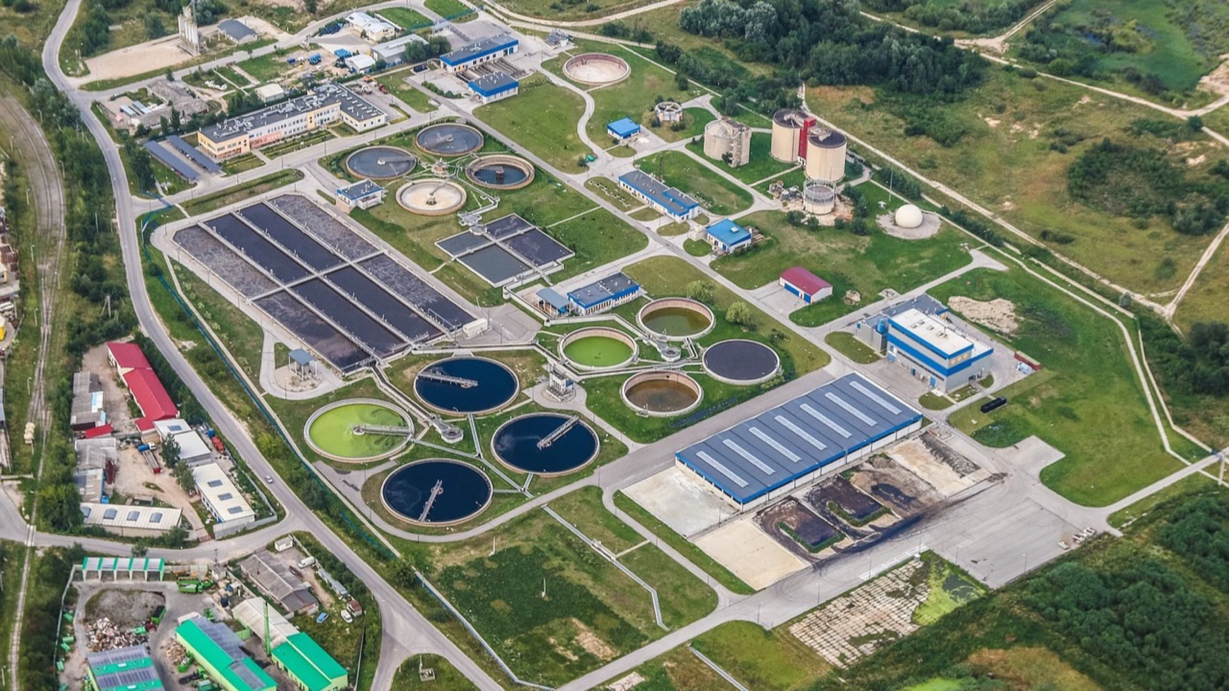 Aerial view of a wastewater treatment plant with circular and rectangular basins.