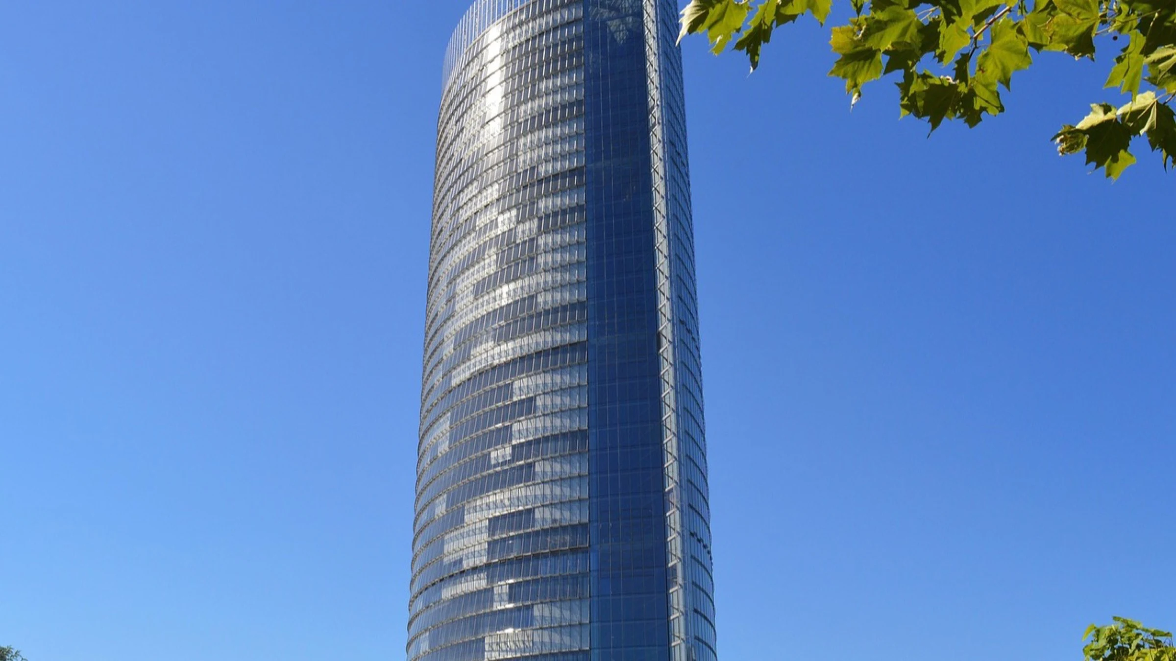 A tall glass communications tower against a clear blue sky.