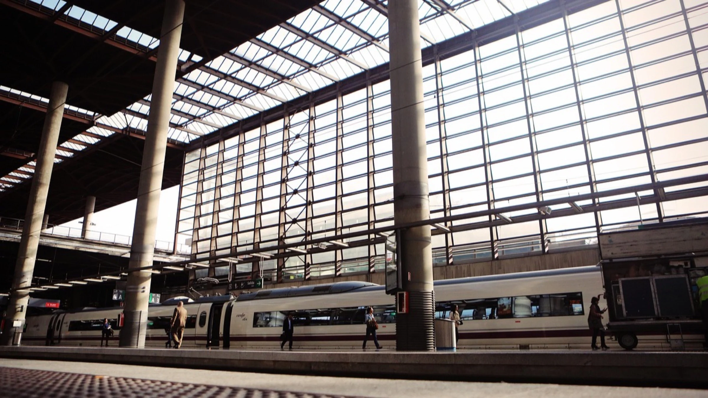 Passenger trains beneath the glass-and-steel roof of a large railway station.
