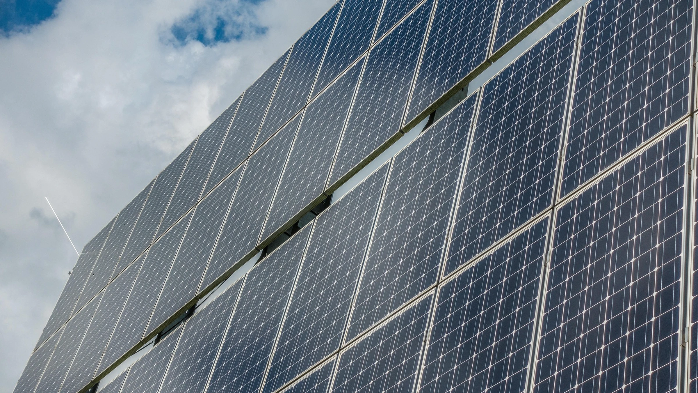 Close view of photovoltaic panels beneath a cloudy sky.