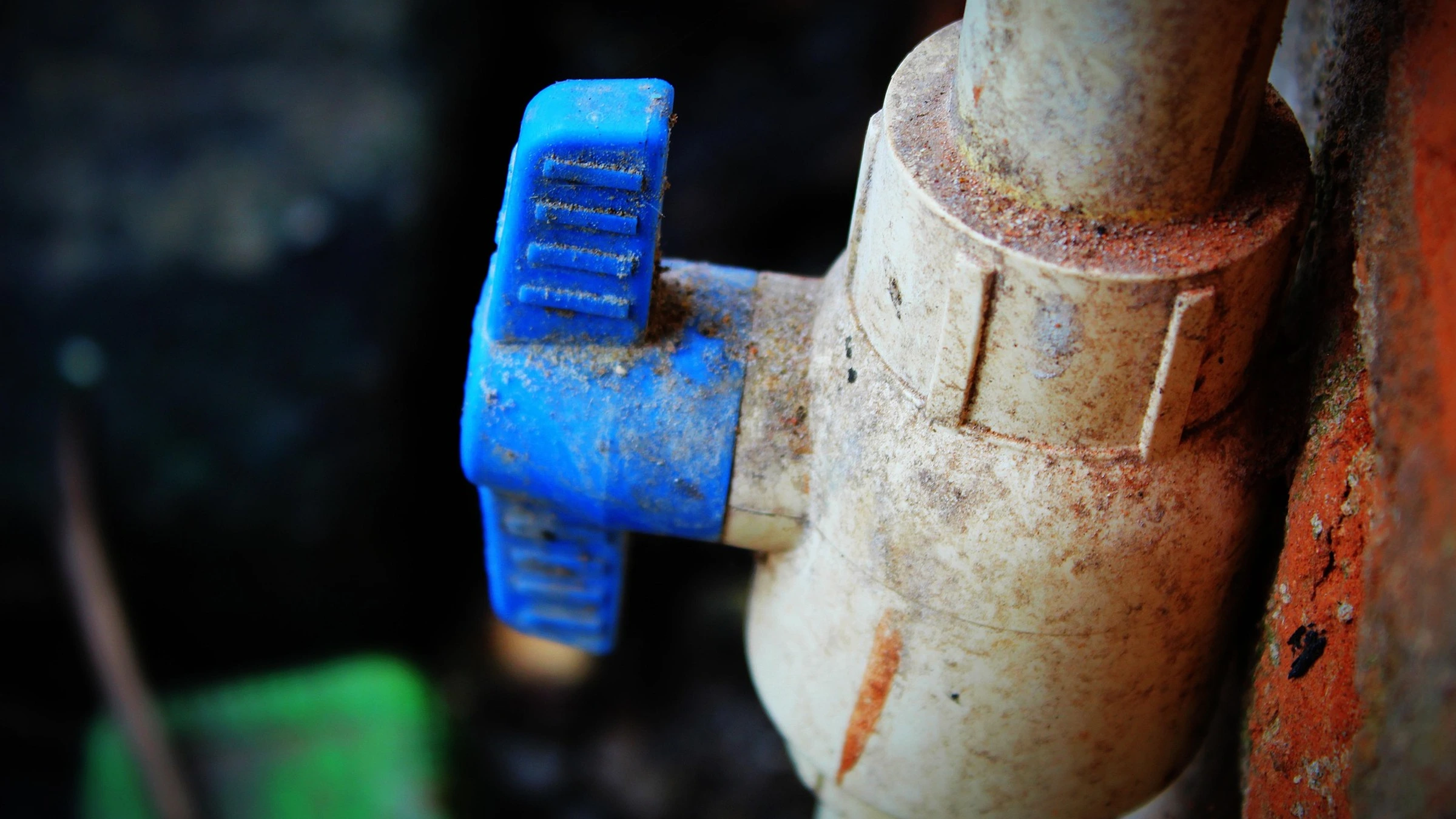 A blue water valve on an outdoor pipe.