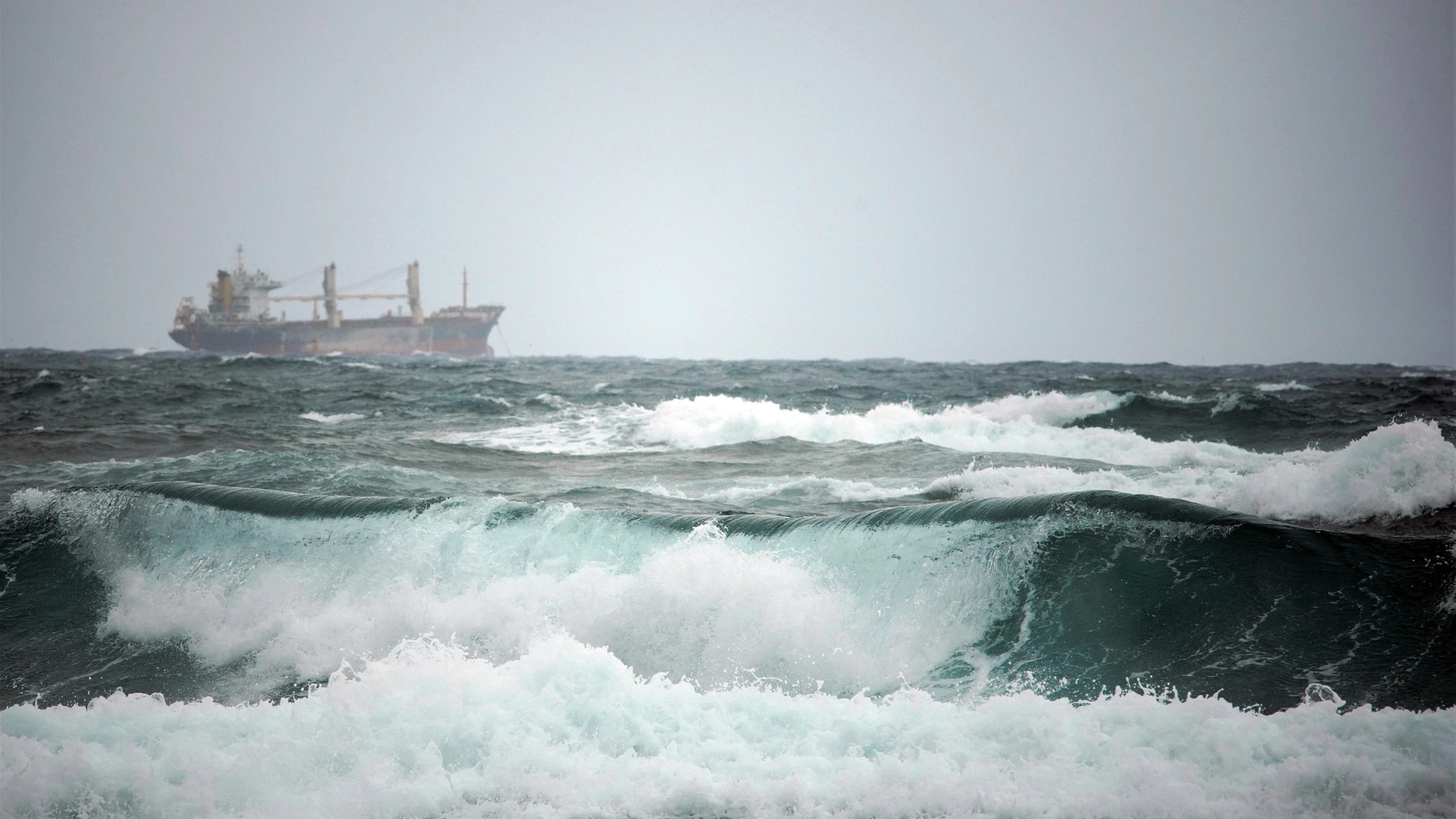 Cargo vessel beyond waves in rough sea