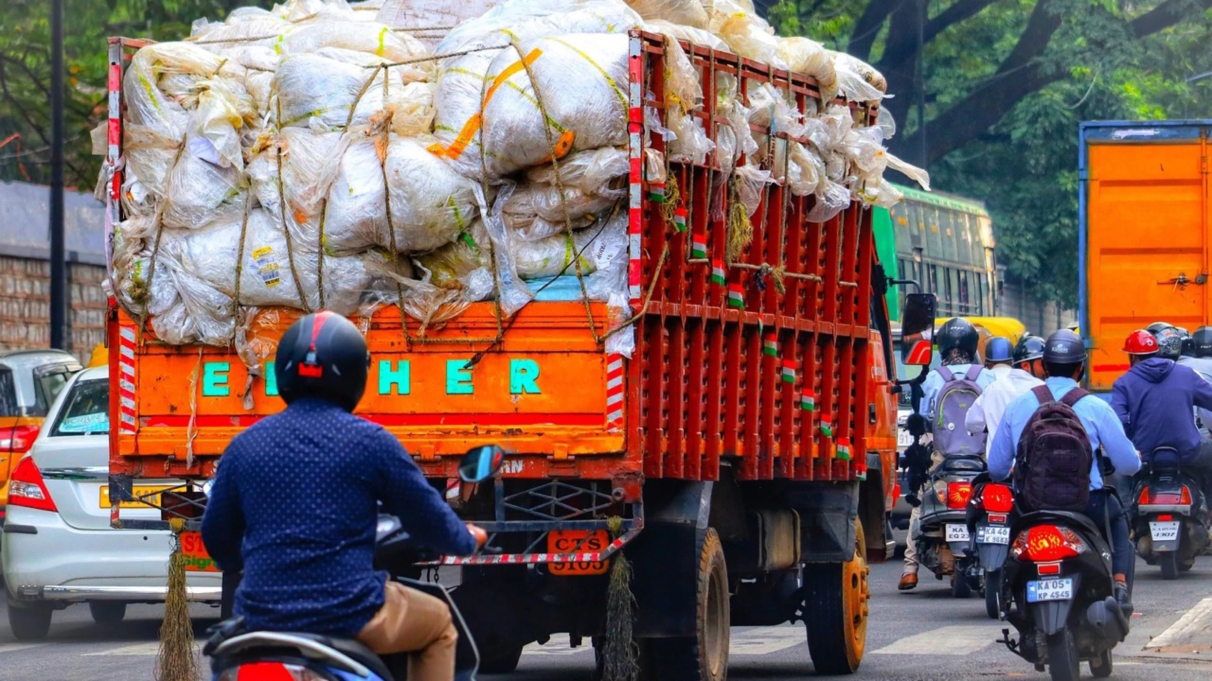 Truck carrying bags of collected material on a busy street