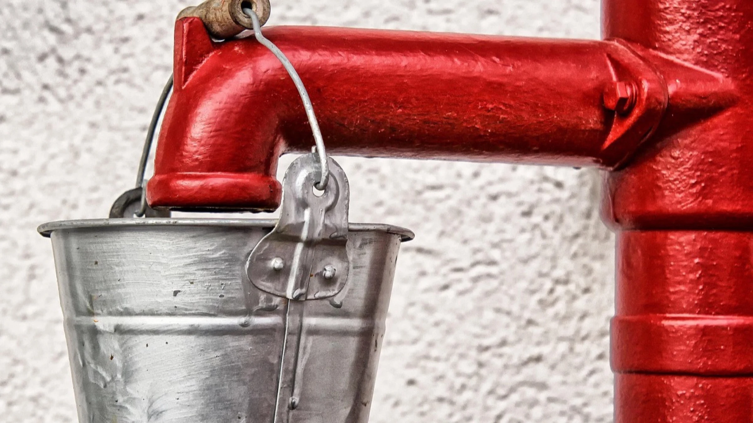 Red water pump with a metal bucket