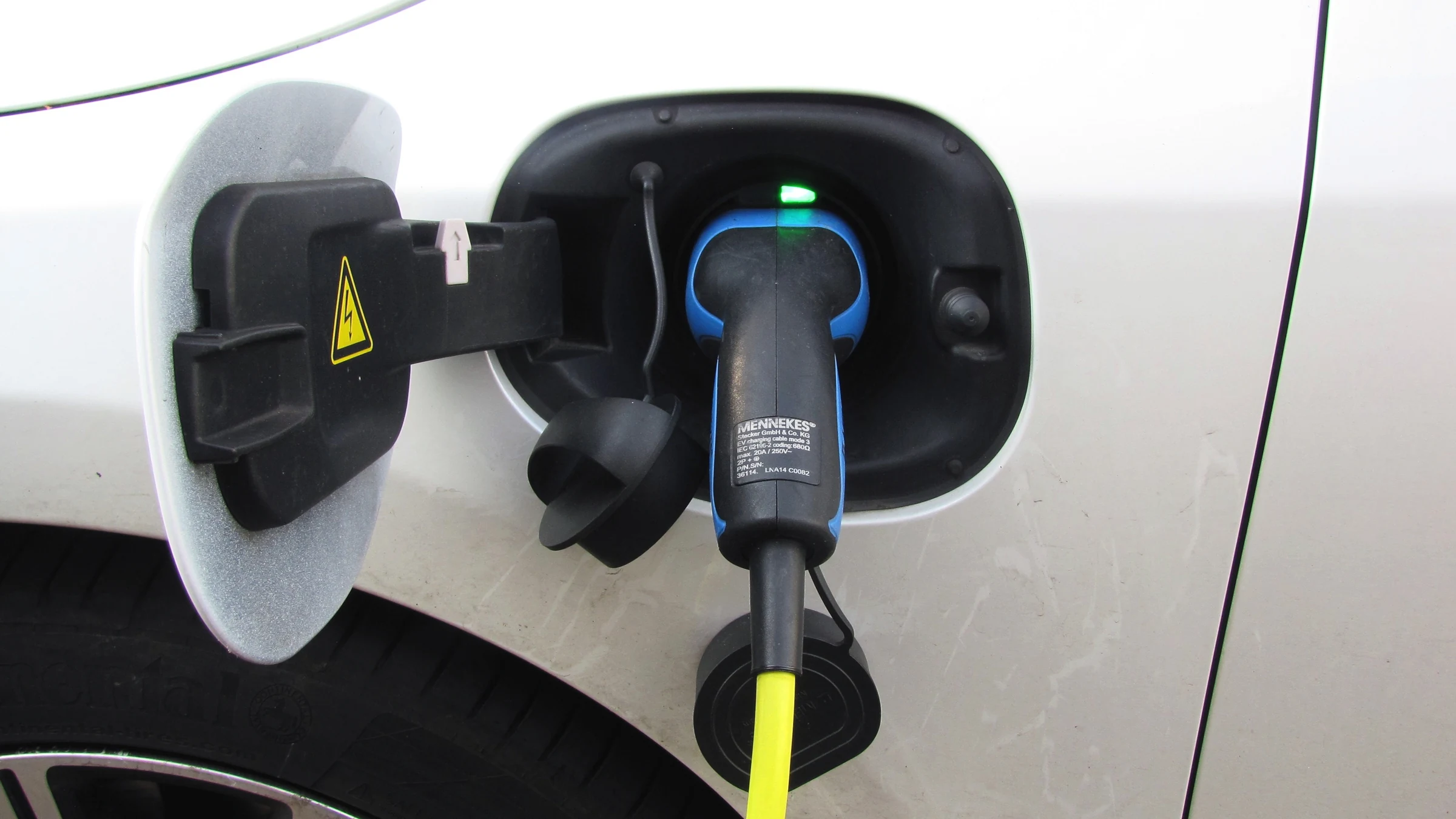 Electric vehicle charging cable connected to a white car