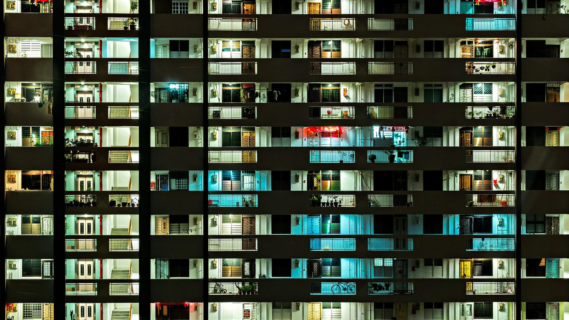 Illuminated apartment balconies in Singapore at night.