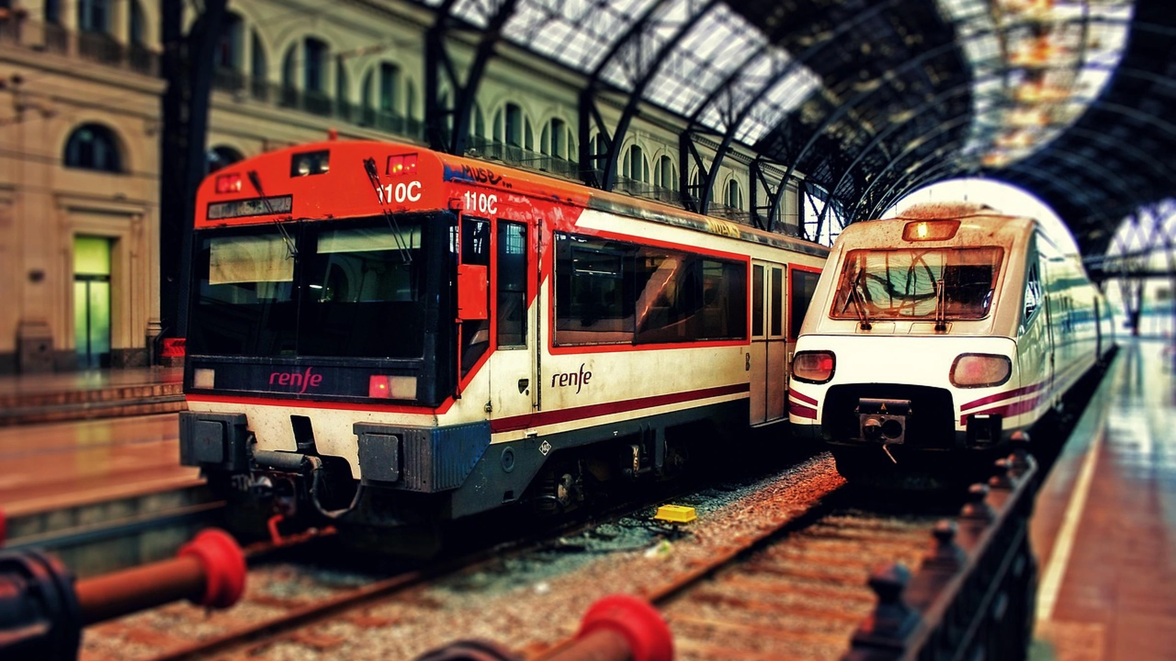 Two trains beside platforms under a station roof in Barcelona