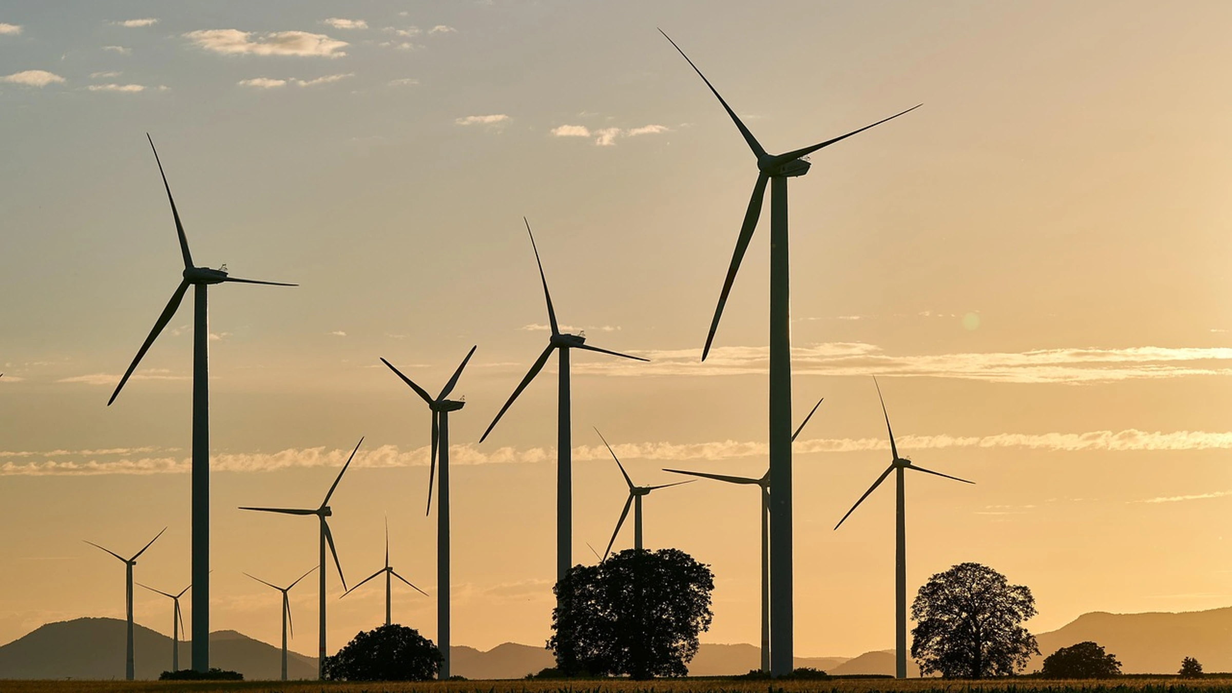 Wind turbines above a rural landscape at sunset