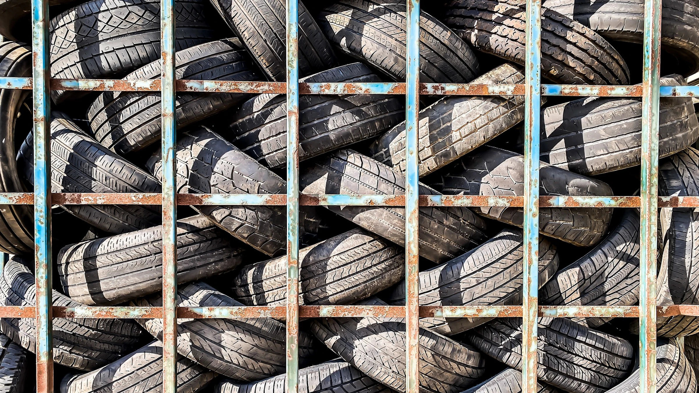 Used vehicle tyres stacked inside a fenced storage area.